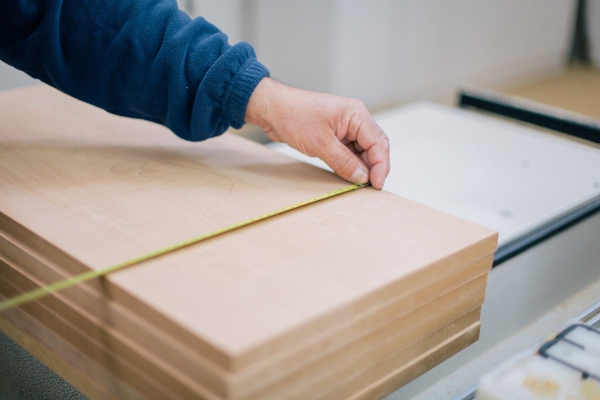 Une main mesure une planche de bois avec une règle Une main mesure une planche de bois avec une règle